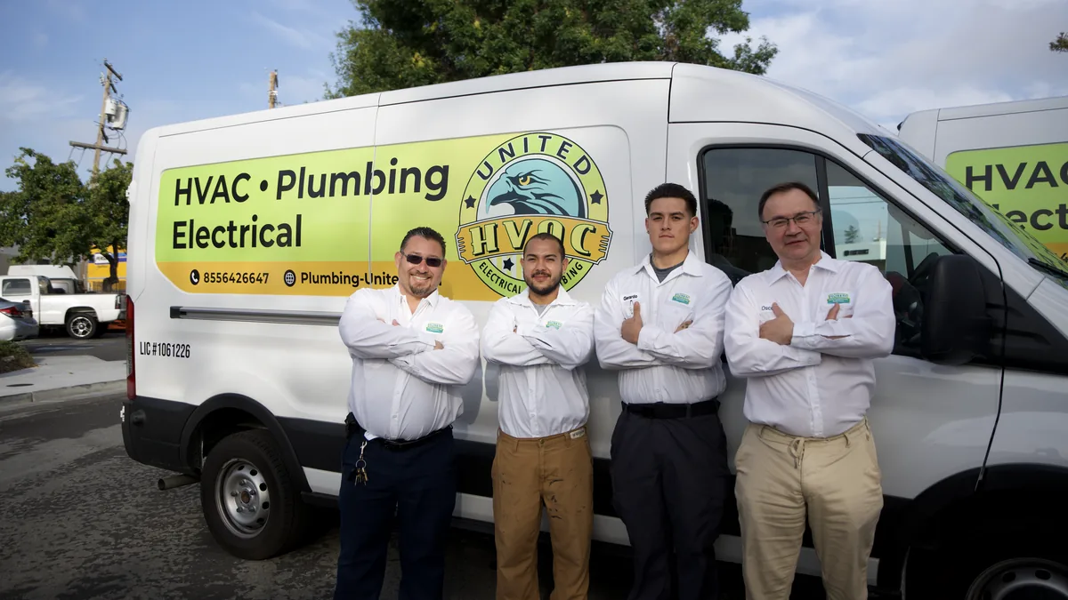 United Plumbing technicians by a branded service van
